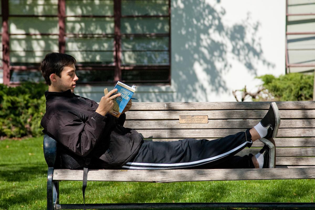 a student reading on a bench.