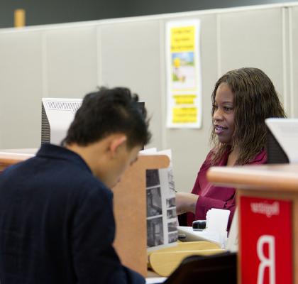 student at registrar window filling out forms.