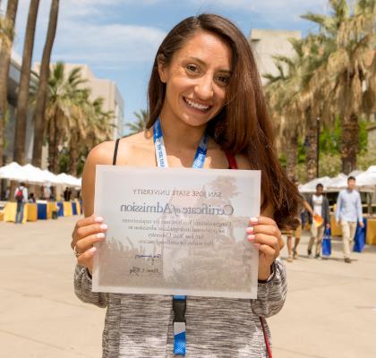 student smiling, holding a certificate of admission to 菠菜网lol正规平台. 